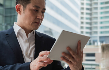 Handsome Asian Businessman Using A Digital Tablet In The City