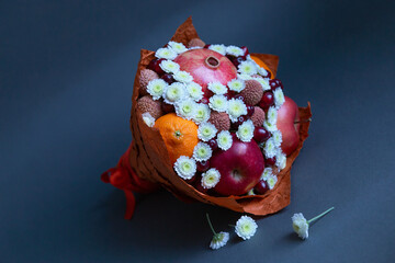Food floristry. Edible bouquet of fruits and flowers on a dark background