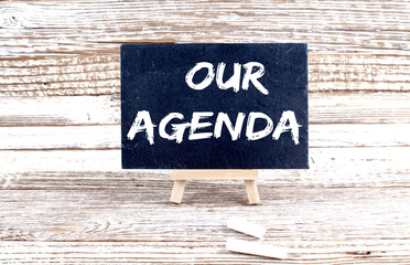 Obraz premium OUR AGENDA text on the Miniature chalkboard on wooden background
