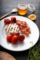 Camembert cheese is round, grilled, poured with golden honey on a wooden cutting board. Soft selective focus, black background.Space for copying. Healthy eating. Vertical photo.
