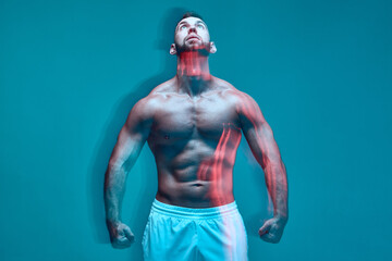Fototapeta na wymiar Powerful athletic man with muscular naked torso looks up in colorful studio light. Long exposure. Sport club advertising