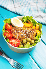 Buddha bowl salad with grilled chicken breast slices, cherry tomatoes, eggs, pepper, olive, lettuce and seeds