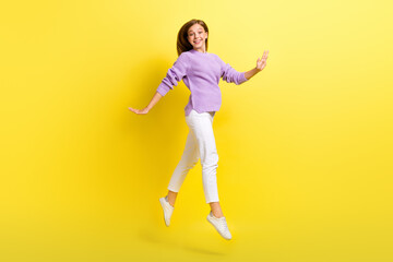 Fototapeta na wymiar Full length photo of cute adorable lady wear stylish violet knitted pullover rejoice free time walking isolated on yellow color background
