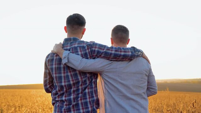 Two young men hugging against the backdrop of the sunset, looking forward to the horizon