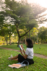 Beautiful portrait photo of a young beautiful asian female thai lady in university student uniform holding a book in a park