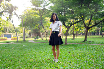 Portrait photo of a young asian beautiful female thai university student lady running happily and relaxingly in a park