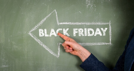 Black Friday. Woman points to text with finger. Green chalkboard