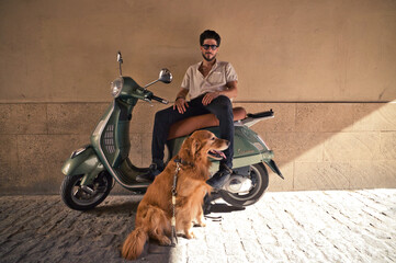 A handsome young man with his brown golden retriever dog. The man is sitting on his retro style...