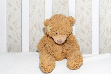 Teddy bear in a white crib, close-up. Children's toys, expectation and birth of a child