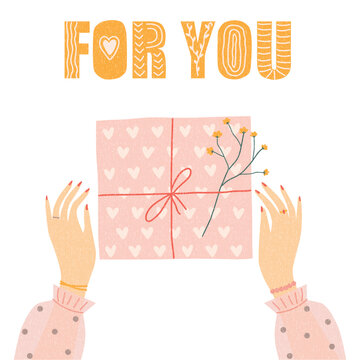 Gift box and female hands, top view. Women's hands are wrapping a gift. The box is decorated with a bouquet of flowers.