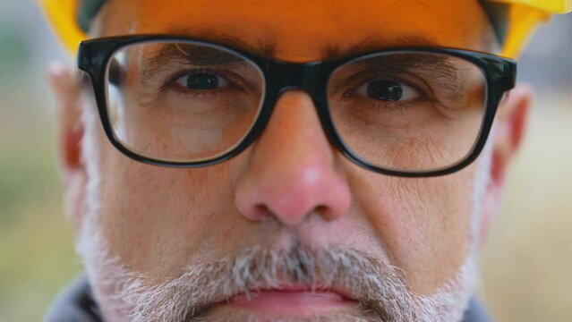 Professional caucasian male engineer looking seriously at camera. Closeup portrait. Blurred background. Gray facial hair, prescription glasses with black frame. . High quality 4k footage