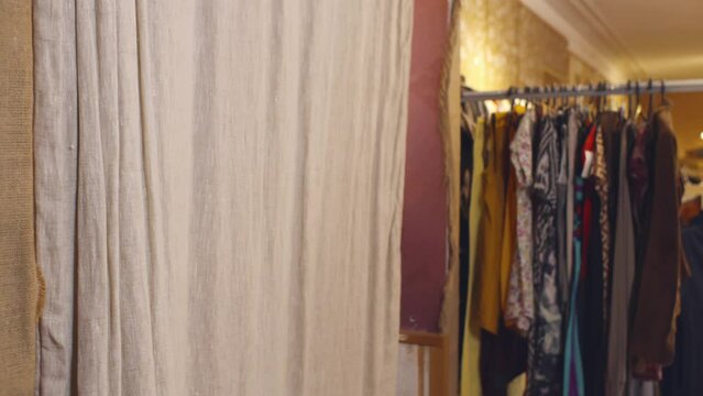 Shop assistant in safety mask and gloves bring clothes to customer in fitting room. Realtime