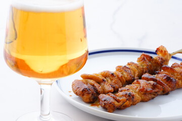 炭火焼にしたタレの焼き鳥（とり皮）をつまみにビールを飲む