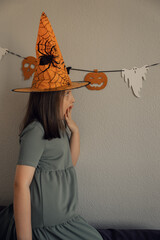 Girl in orange hat is surprised, halloween concept. High quality photo