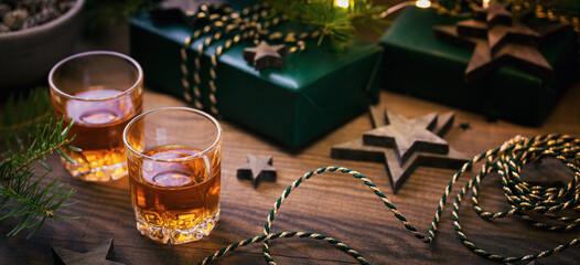 Whiskey, brandy or liquor shot and Christmas decorations on wooden background. Winter holidays concept.