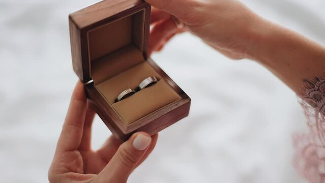 The girl holds a box with rings in her hands and carefully opens it. Shooting a box in the hands of a girl