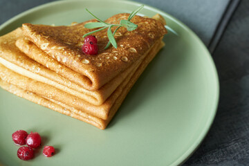 Pancakes close-up decorated with a berry and a sprig of rosemary.