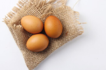 Three eggs laid on a sackcloth on a white table.