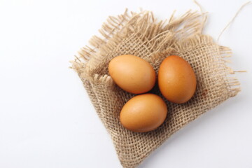 Three eggs laid on a sackcloth on a white table.