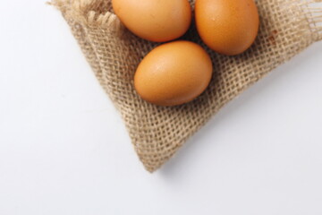 Three eggs laid on a sackcloth on a white table.
