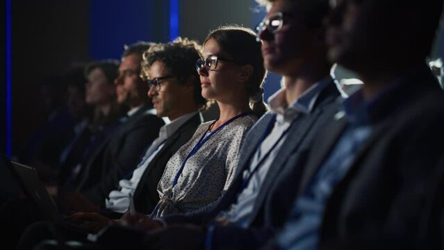 Young Woman Sitting in Crowded Audience at a Human Resource Conference. Female Delegate Using Laptop Computer. HR Manager Listening to Inspirational Entrepreneurship Presentation About Social Studies.