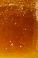 Surface texture of liquid light golden color with air bubbles of bee honey. Healthy food.