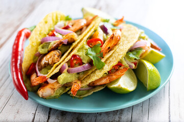 Mexican tacos with shrimp,guacamole and vegetables on wooden table