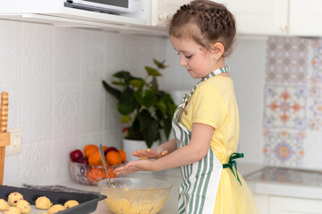 Happy child playing with flour in kitchen. kid cooking food. little cute girl in apron in preparing dough, baking pie, oatmeal cookies, making biscuit