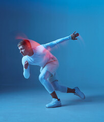 Sprinter start. Male strong muscular athlete starts running on blue background.