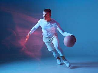 Fototapeta na wymiar Concept of health, professional sport, hobby. Basketball player with ball in white sportswear on blue background.