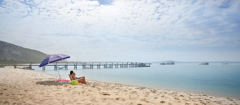 Couple sitting and relaxing on sunny, sandy ocean beach