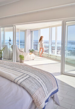 Woman standing at sunny patio door with ocean view