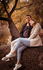 Young couple in love outdoors. Stunning sensual portrait of a young stylish fashionable couple, side view in the park in autumn near the lake