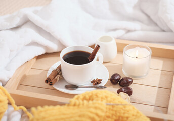 cozy lazy winter morning with coffee and knitting in bed. warm ambient home. candle and dry fruits on wooden serving tray.
