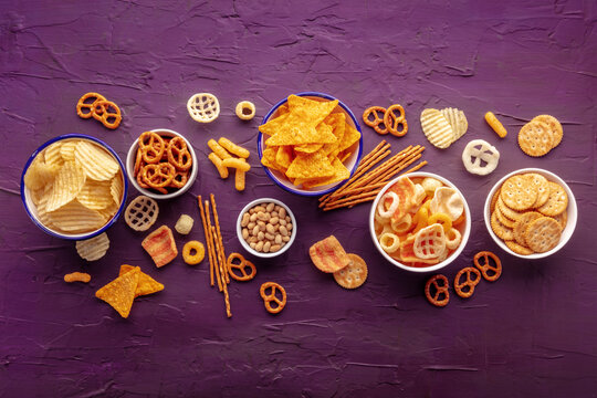 Salty Snacks. Party Food Mix Background. Potato And Tortilla Chips, Crackers And Other Appetizers In Bowls, Overhead Flat Lay Shot