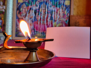 Picture of Diya lamp. Diwali Celebration. A blank placard in background for writing custom messages. Sculpture of Gods and goddess in background