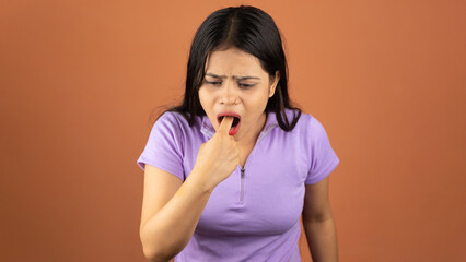 Young sick woman, annoyed frustrated, disgusted, fed up, sticking fingers in her throat, about to throw up, Isolated color background