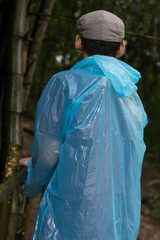 The person walking in the park wears a raincoat light blue.