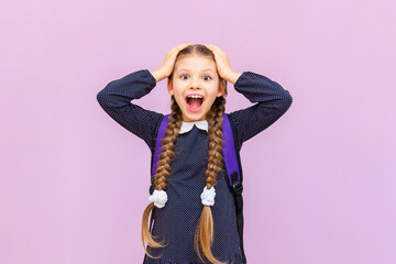 The schoolgirl is very surprised and confused, the girl in a polka dot dress on an isolated background.