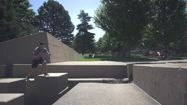 Slow motion of a young active Caucasian guy jumping over a monument in the park