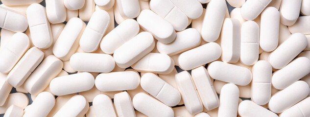 Medicine background from bunch white pills, macro. Drug production backdrop.