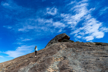 brave backpacker girl descends from frenchman peak in cape le grand national park in western australia, hiking and climbing a mountain with a backpack