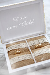 Golden wedding rings in a wooden box with the words Love Over Gold