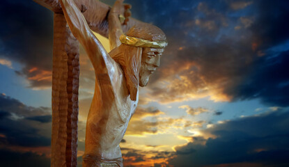 Jesus Christ on the Cross sculpture against the sunset sky in background