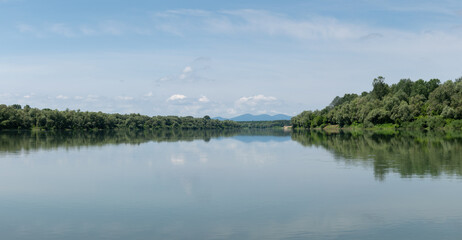 Fototapeta premium Landscape of Sava river and distant mountain Motajica silhouette in haze, during sunny summer day