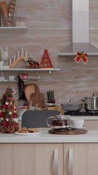vertical video: Empty xmas decorated kitchen with nobody in it is ready for christmas morning dessert. On table baked cookie dessert with cup of coffee waiting for guest during winter holidays