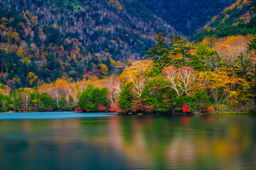 Autumn in Lake District.Colourful trees reflecting in calm water surface.Bright and vibrant landscape scene.Nature background.Autumn walk.