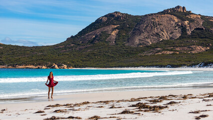A long-haired girl in a dress dances, runs and fools around on a paradise Australian beach; white...