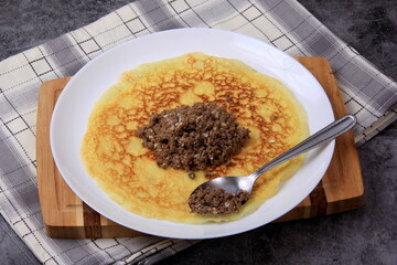 Minced meat filling on a large thin pancake. Making a pancake filled with meat or heart