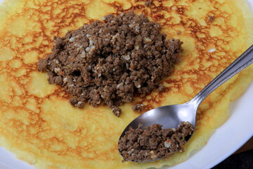 Minced meat filling on a large thin pancake. Making a pancake filled with meat or heart